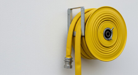 Yellow fire hose reel on white wall