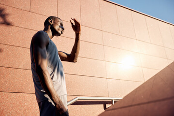 Athletic individual shielding eyes from sun in urban environment