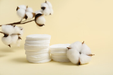 Cosmetic pads and cotton branch on color background