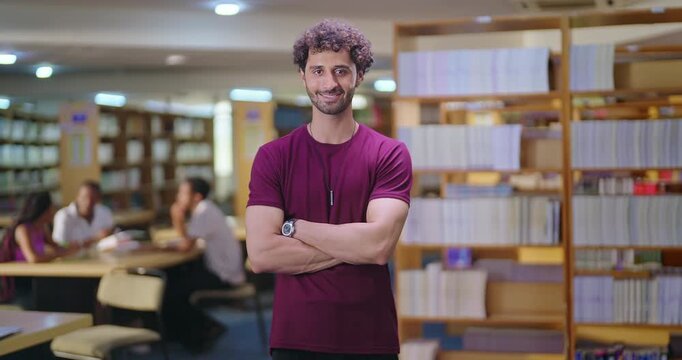 Indian asian young adult gen z man confident student standing proud fold hand look camera indoor book store library happy smiling boy cross arm staring cam do casual pose enjoy day time inside college