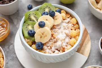 Healthy cereal bowl with yogurt and fresh fruits on grey background, closeup