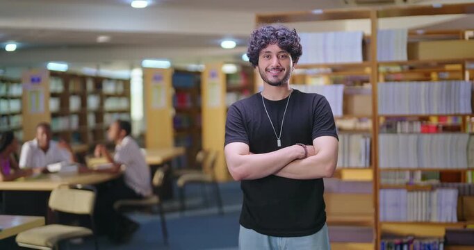 Indian asian young adult gen z man confident student standing proud fold hand look camera indoor book store library happy smiling boy cross arm staring cam do casual pose enjoy day time inside college