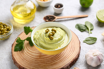 Bowl of tasty peas hummus with garlic on grey background