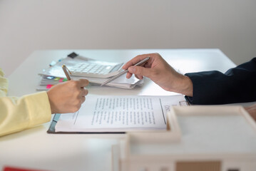 Business Negotiation. Client and agent discussing contract details with documents and pens.