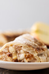Homemade apple strudel slices in plate on wooden table. Traditional Austrian and German sweet