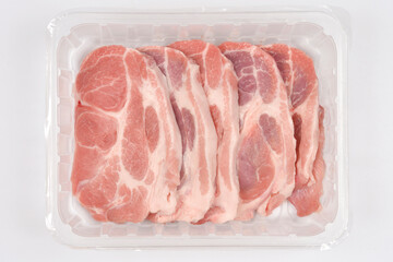 A top-down view shows slices of raw pork neck in a transparent plastic tray against a gray...