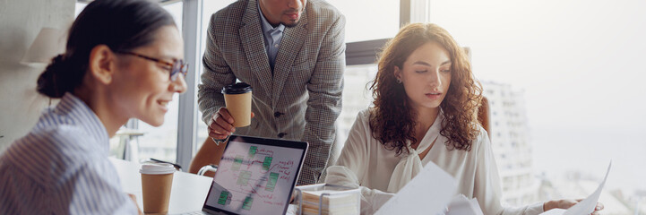 A team gathers together to discuss various work strategies over coffee in a modern, inviting office setting