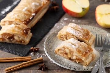 Homemade apple strudel slices in plate on wooden table. Traditional Austrian and German sweet
