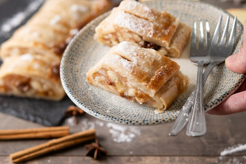 hand holding a plate with some slices of apple strudel