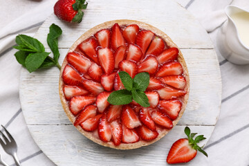Wooden board of sweet strawberry tart with mint on napkin, closeup
