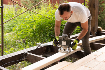 Carpenter at work on manual milling machine for wood. Close-up of milling slot in pine board for...