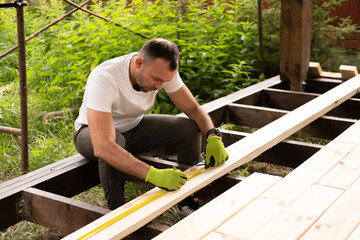 Man carefully marks plans on stand, planning detailed repair while working with wood. Measuring and...