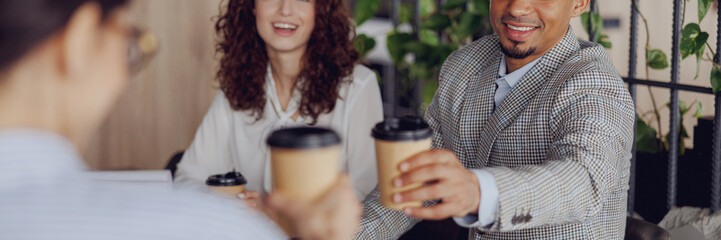 In a modern office, a friendly group enjoys coffee, fostering connection and collaboration among them
