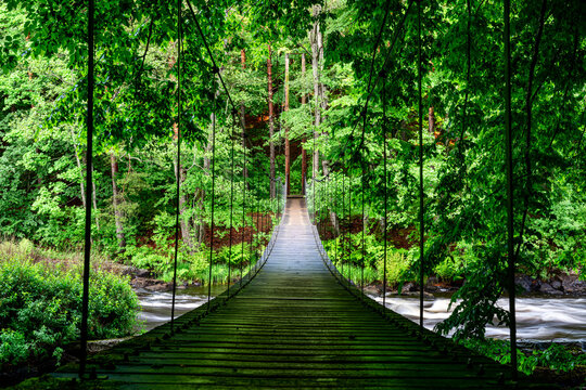 Holz H&auml;ngebr&uuml;cke &uuml;ber Fluss mitten im Wald in Schweden bei M&ouml;rrum