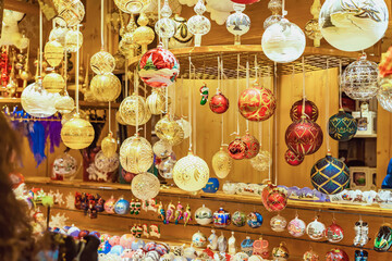 Elegant Christmas baubles in gold, red and white colors hanging at handcrafted ornament stall. Concept of Christmas fair, festive glass decor and traditional holiday beauty