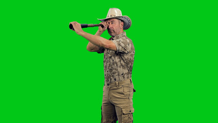 A hiker in camouflage uniform with cowboy hat gazing into far horizon through telescope against...