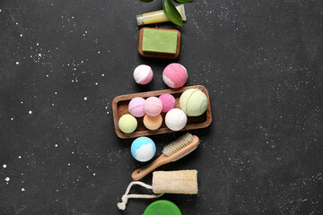 Bath bombs with massage brush, soap and loofah on dark background