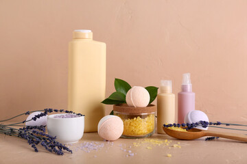 Bath bombs with lavender flowers, sea salt and bottles of cosmetic products on beige table