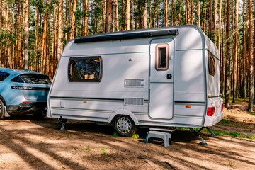 Caravan RV parked under trees in summer forest. Family traveling with motorhome. Travelers on an...