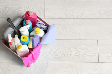 Basket with different cleaning supplies on floor, closeup