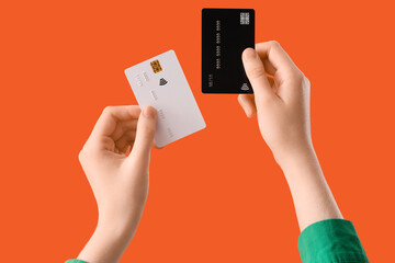 Female hands with credit cards on orange background, closeup