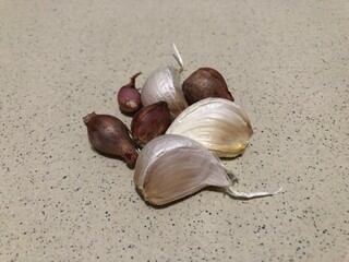 Garlic cloves and shallots on a speckled surface