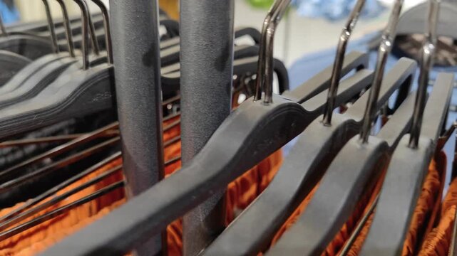 A row of multiple clothes hangers displayed in a garment industry store. Industrial clothing hangers used for organizing apparel in fashion retail and textile production.