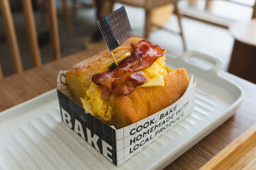 A slice of delicious, fresh bacon with egg toast on a wooden table