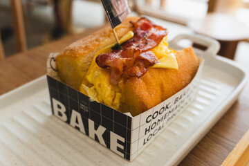 A slice of delicious, fresh bacon with egg toast on a wooden table