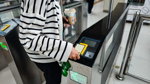 The women checking in the metro station. Tapping card for payment and for passing through the turnstile in the Jakarta bus stop. Public transportation terminal machine.