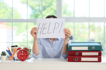 Businesswoman holding paper with word HELP in office. Time management concept