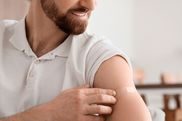 Young man with applied medical patch after vaccination at home, closeup