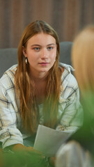 Teenage girl with serious face during session with psychologist. Concept of psychotherapy,...