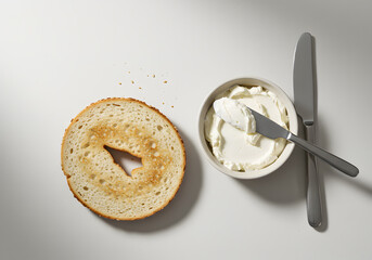 Bagel with cream cheese and knife on white background