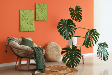 Interior of living room with Monstera plant, armchair and paintings