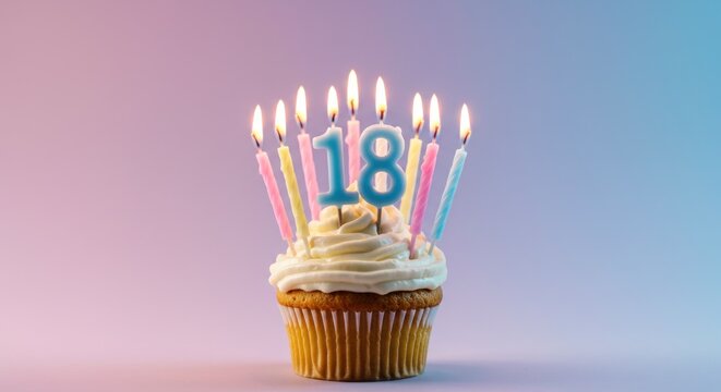 A single cupcake with vanilla frosting, topped with lit pastel candles forming the number 18 against a soft purple and pink gradient background