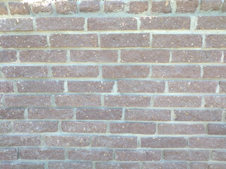 wall of old dark brown brick. background texture. between rows of bricks light stripes of hardened cement mortar. wall of building or fence