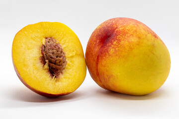A ripe nectarine with vibrant orange and red hues, placed against a clean white background. Sliced.