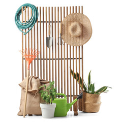Wooden fence with plants and gardening supplies on white background