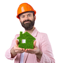 Portrait of young construction engineer wear orange hard hat, in a pink jacket standing on red studio background. A man holds a green eco house.