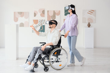 Young man in wheelchair and woman with VR glasses visiting modern art gallery