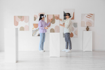 Young couple with VR glasses near paintings in modern art gallery