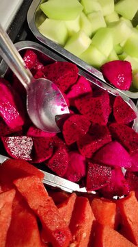 vertical video Close-up view of freshly cut dragon fruit and watermelon arranged together. The vibrant red and purple colors highlight freshness, health, and natural nutrition.