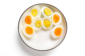 Top-view of assorted hard-boiled egg halves on a white ceramic plate; bright, high-key studio lighting with clean minimal styling and vivid yolk shades.