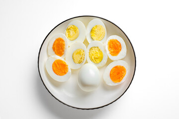 Overhead shot of hard-boiled eggs arranged in a ring around a whole egg on a white plate; crisp, minimalist food styling with vibrant orange yolks.
