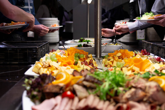 Guests at a business event or conference enjoying a buffet with a variety of snacks, cheese, and fruits. Catering services and corporate event concept.
