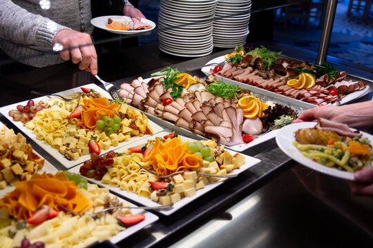 Guests at a business event or conference enjoying a buffet with a variety of snacks, cheese, and fruits. Catering services and corporate event concept.
