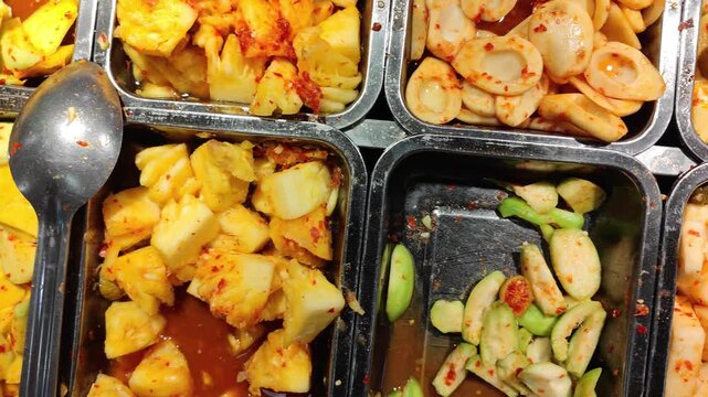 Close-up of traditional Indonesian fruit pickles (asinan) made from a variety of tropical fruits such as mango and guava, seasoned with chili and spices. A popular street food snack in Indonesia known