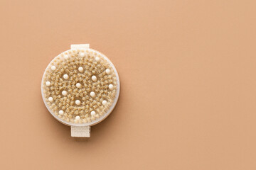 Massage body brush on brown background, closeup