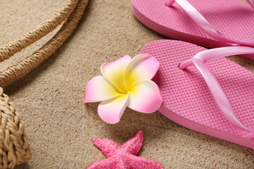 Plumeria flower with flip-flops on sand, closeup